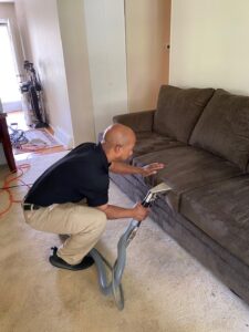 Carpet cleaning technician using professional equipment to deep clean a sofa, removing stains and revitalizing the upholstery for a fresh, restored look.